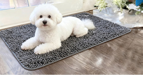 Small white dog lying on a grey chenille hair-trap mat
